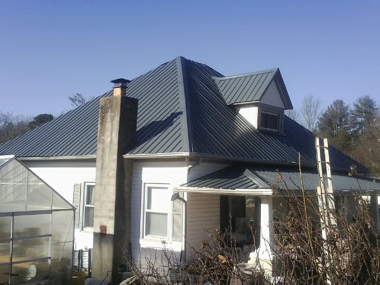 Dark blue standing seam metal roof on a white farmhouse with dormer — Slate & Tile Roof Repair by Roofing Brothers in Wrenshall