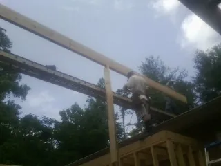 Carpenter setting a ridge beam over a new addition frame — Ice Dam Removal by Roofing Brothers in Wrenshall
