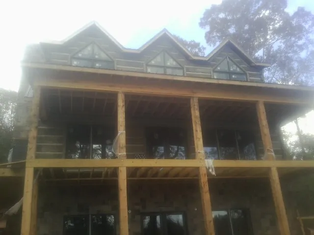 Dormers and porch framing on a large log home under construction — Roof Coating work by our crew in Wrenshall