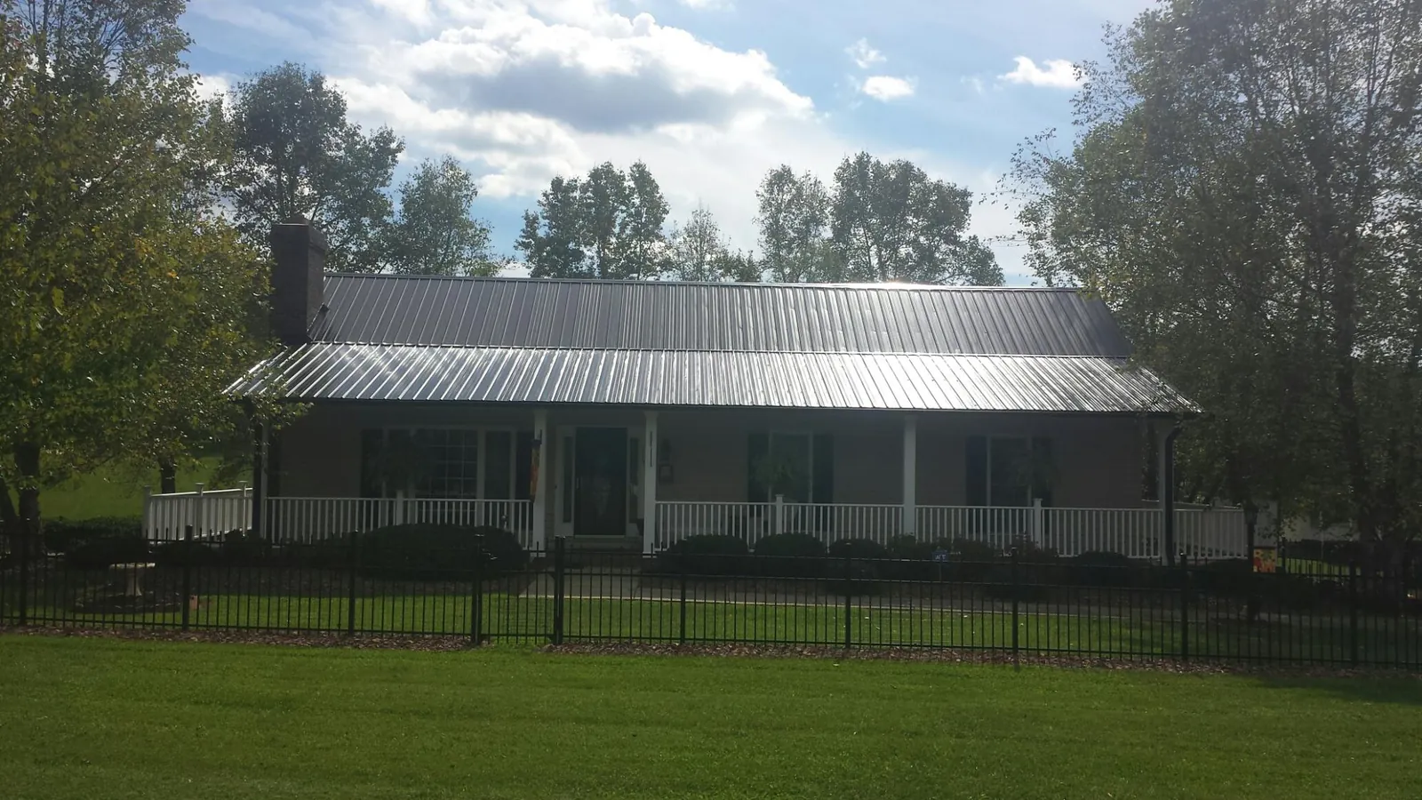 Gray metal roof on a brick ranch with a full width front porch — Gutter Guard Installation work by our crew in Wrenshall